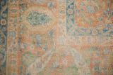 Distressed vintage carpet showing even wear across the pale terra cotta and blue knot heads.