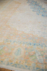 Detail of the distressed texture and scalloped medallion in pale terracotta, ivory, and blue.