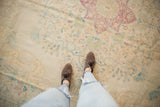 Distressed vintage Bulgarian Kerman carpet with faded raspberry, ivory, and sky blue millefleur motifs.