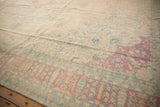Faded blush, ivory, and powder blue floral motifs on a distressed Kerman rug.