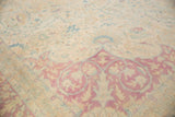Distressed Bulgarian Kerman rug corner, ivory and faded raspberry millefleur pattern.