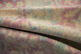 Distressed vintage rug pile with faded raspberry, blush, and powder blue Kerman patterns.