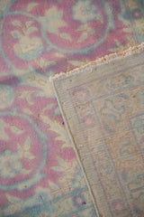 Distressed pink and blue floral pattern on a vintage Kerman rug, exposing its tight woven back.