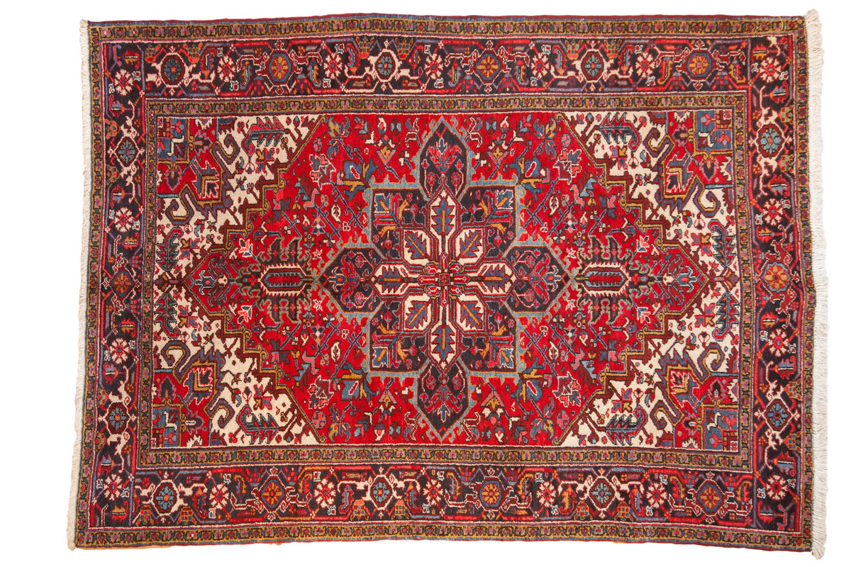 Vintage Persian Mehrivan rug with a serrated navy medallion on a cherry red field and geometric turtle border.