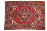 Vintage Persian Mehrivan rug with a serrated navy medallion on a cherry red field and geometric turtle border.