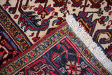 Folded corner of a vintage Mehrivan carpet revealing its navy turtle border and plush pile.