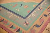 Geometric hook-and-latch motifs on a vintage Dhurrie carpet in pale turquoise and dusty gold.