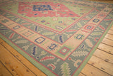 Dhurrie rug corner with stepped diamond, boteh, and geometric patterns in pale raspberry, navy, and sage.
