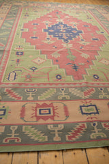 Geometric border pattern of the dhurrie rug in sage green, apricot, and dusty navy.