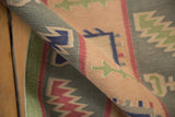 Rolled vintage Indian Dhurrie flatweave, with geometric patterns in pale sage, dusty raspberry, and navy.