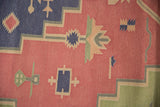 Flat-woven texture with simplified plants and geometric motifs in dusty raspberry and navy.