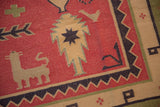 Geometric animal and tree-of-life motifs on a dusty raspberry Dhurrie flatweave.