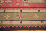 Vintage Dhurrie rug detail with a geometric star motif and patterned bands in sage green, red, navy, beige.