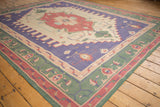 Dhurrie carpet corner with mallard green selvage and dusty raspberry geometric border.