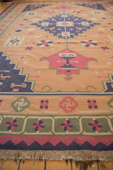 Fringed edge of vintage Dhurrie with geometric green, faded raspberry, and dusty navy borders.