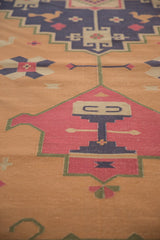Vintage Dhurrie carpet detail showcasing geometric motif in faded raspberry, dusty navy, and gold.