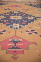 Angled view of the vintage Dhurrie rug's faded raspberry, navy, and gold geometric motif.