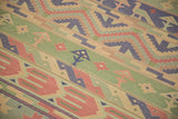 Hand woven vintage Dhurrie carpet with geometric bands, showing bird and plant motifs in seafoam and red.