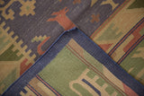 Folded vintage Dhurrie rug corner with blue selvage, flatweave, and abstract patterns.