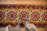 Saffron yellow field with navy, copper, and red starburst medallions and geometric motifs.