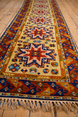 Vintage Siberian Kazak runner with geometric saffron field, navy blue border, intact selvage, and fringe.