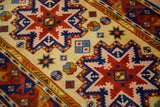 Chestnut red, pale pink, and navy blue geometric Kazak design with starburst and pinwheel motifs.
