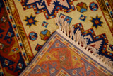 Vintage Kazak rug corner showing geometric patterns, saffron yellow field, and woven back.