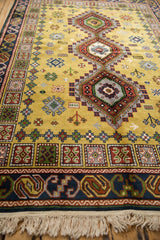 Cream fringe and dark blue border featuring rust, gold, green tribal geometric motifs.