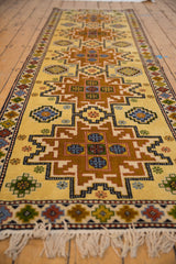 Saffron yellow field, geometric starburst design, and cream fringe on this vintage Kazak runner.