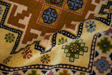 Close-up of hand-knotted Kazak rug's thick saffron yellow pile and geometric motifs.