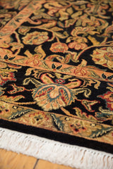 Intricate gold, red, blue palmettes and vinery on navy black Arts and Crafts rug, white fringe.