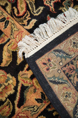 Intricate scrolling palmettes, fringe, and geometric patterned back of Indian Arts and Crafts rug.