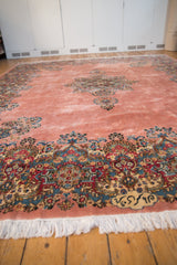 Intricate millefleur border and weaver's signature on a dusty rose Persian Kerman rug.