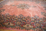 Sprawling dusty rose field of a vintage Kerman with its intricate millefleur border in the foreground.
