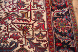 Intricate geometric floral details in navy blue and red on the full, plush pile of a vintage Mehrivan rug.