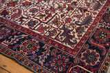 Close-up of the geometric floral palmettes on the navy border and ivory field of a Persian rug.