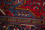 Detailed view of hand-knotted serrated leaves in sapphire blue, wine red, and gold on a vintage Mehrivan.