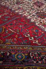 Close-up of serrated leaf motifs in wine red, sapphire blue, and gold on a vintage Mehrivan carpet.