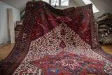 A draped vintage Mehrivan carpet showing its grand scale, central medallion, and wine red field.