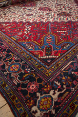Corner detail of a vintage Persian carpet showing intricate borders in sapphire blue and wine red.