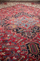 Vintage Mehrivan carpet with geometric serrated leaves, blossoms, and vinery in cherry red and navy.