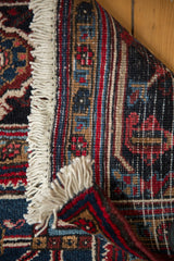 Mehrivan rug detail: hand knotted back, cherry red, navy blue geometric pattern, ivory fringe.