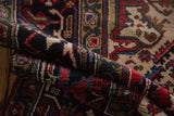 Folded vintage Mehrivan carpet, hand-knotted pile with red, navy, and ivory floral motifs.