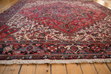 Lush, full pile of a vintage Persian Mehrivan rug showing its geometric navy border and ivory fringe.