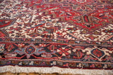 Low angle on a vintage Mehrivan carpet's corner, highlighting the full pile and geometric border.