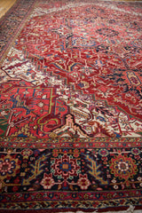 Angled view across the full, plush wool pile of a vintage Heriz carpet, showing its dense ruby and navy design.