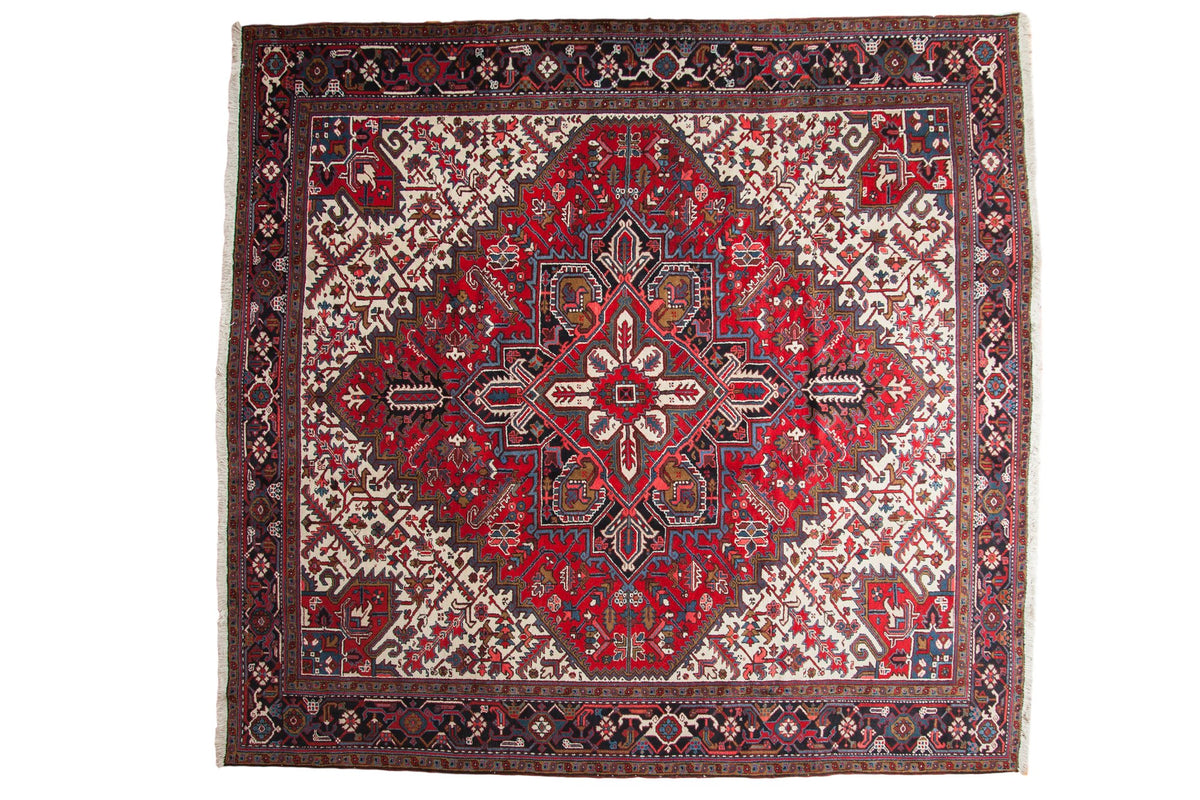 Vintage Persian Mehrivan square carpet with a geometric starburst medallion in red, navy blue, and ivory.