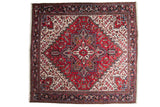 Vintage Persian Mehrivan square carpet with a geometric starburst medallion in red, navy blue, and ivory.