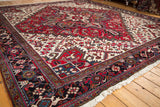 Angled view of a vintage Mehrivan carpet with geometric vinery and a multi-layered border.
