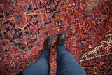 Textured pile of vintage Heriz carpet with geometric vinery in brick red, navy blue, and blush.